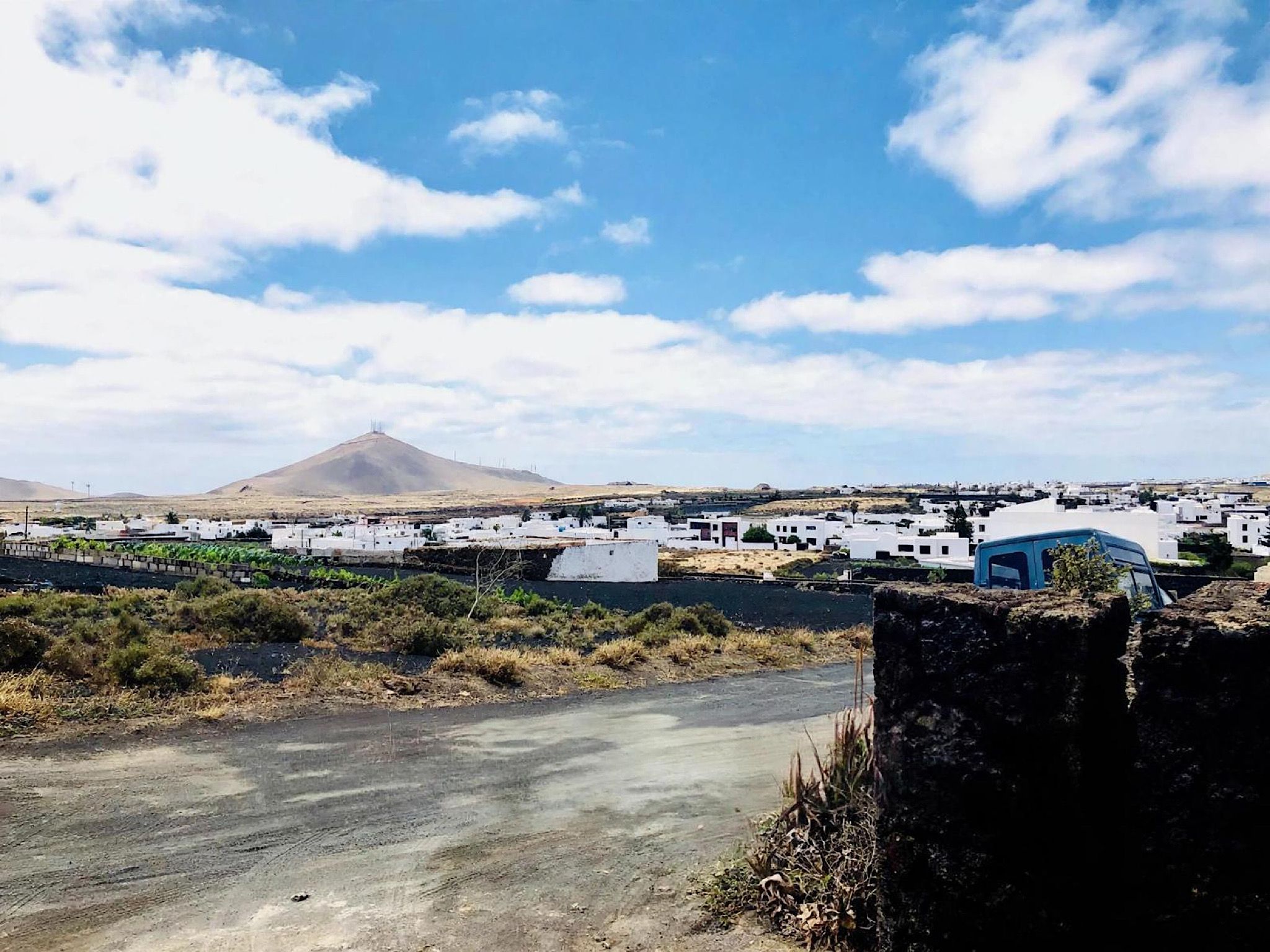 Paisaje desértico con una montaña al fondo y un complejo de edificios blancos en primer plano.