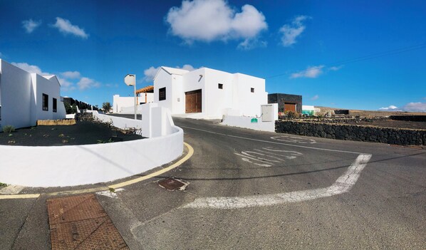 A white building with a curved driveway and a stone wall. - Casita Bellavista With Great Views in Mozaga (Teguise)