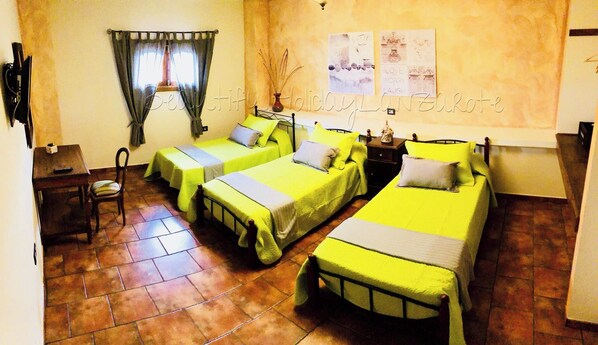 A room with three single beds, a small table, a chair, and a window with curtains. - Casita Bellavista With Great Views in Mozaga (Teguise)