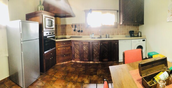 Una cocina compacta equipada con refrigerador, horno, microondas, lavaplatos y lavadora.