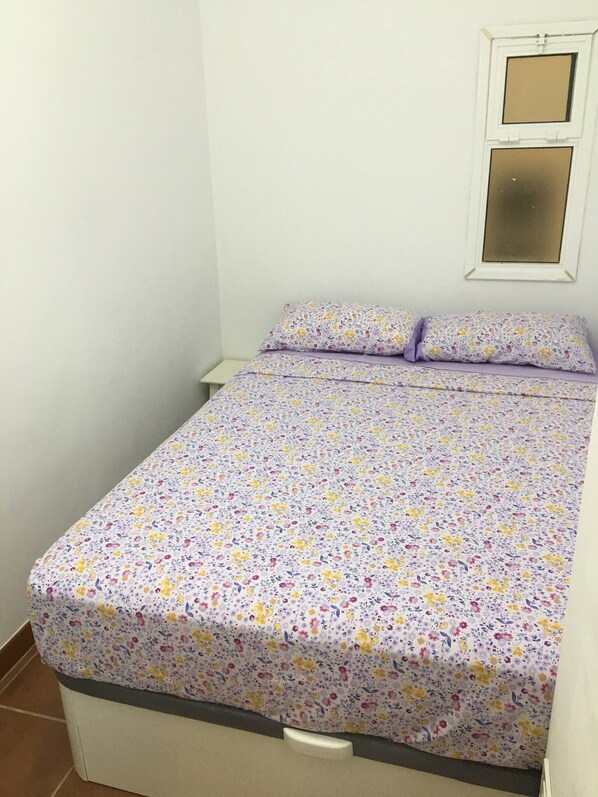 A small, single-bed room with a floral-patterned bedspread and matching pillows. - 2 Bd Apartment With Stunning View (Santiago del Teide)