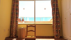 A room with a bed, a chair, a window with curtains, and a view of the outside. - 2 Bd Apartment With Stunning View (Santiago del Teide)