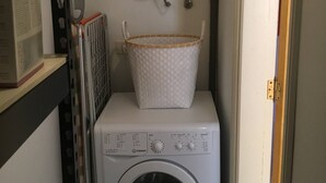 A compact laundry area with a white washing machine, a drying rack, and a water heater mounted above. - 2 Bd Apartment With Stunning View (Santiago del Teide)