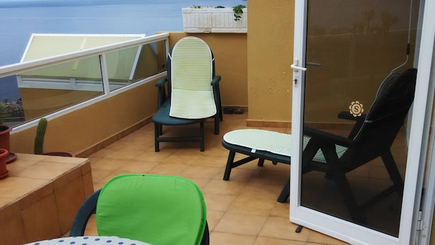 A balcony with a table, chairs, and a sliding glass door. - 2 Bd Apartment With Stunning View (Santiago del Teide)