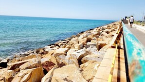 A coastal walkway with large rocks and a clear view of the sea. - Townhouse With Shared Pool (Torrevieja)