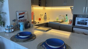 Eine moderne Küche mit Einbauofen, Spüle und Kaffeemaschine. Dekorationsgläser und ein Schild an der Wand sind vorhanden.