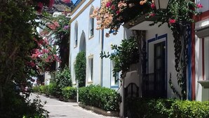 A narrow street with buildings on either side, some with balconies and flower boxes. - Mirador Studio Apartment (Mogan)