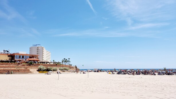 Ein Strand mit einem Hotel namens "La Zambra" im Hintergrund.