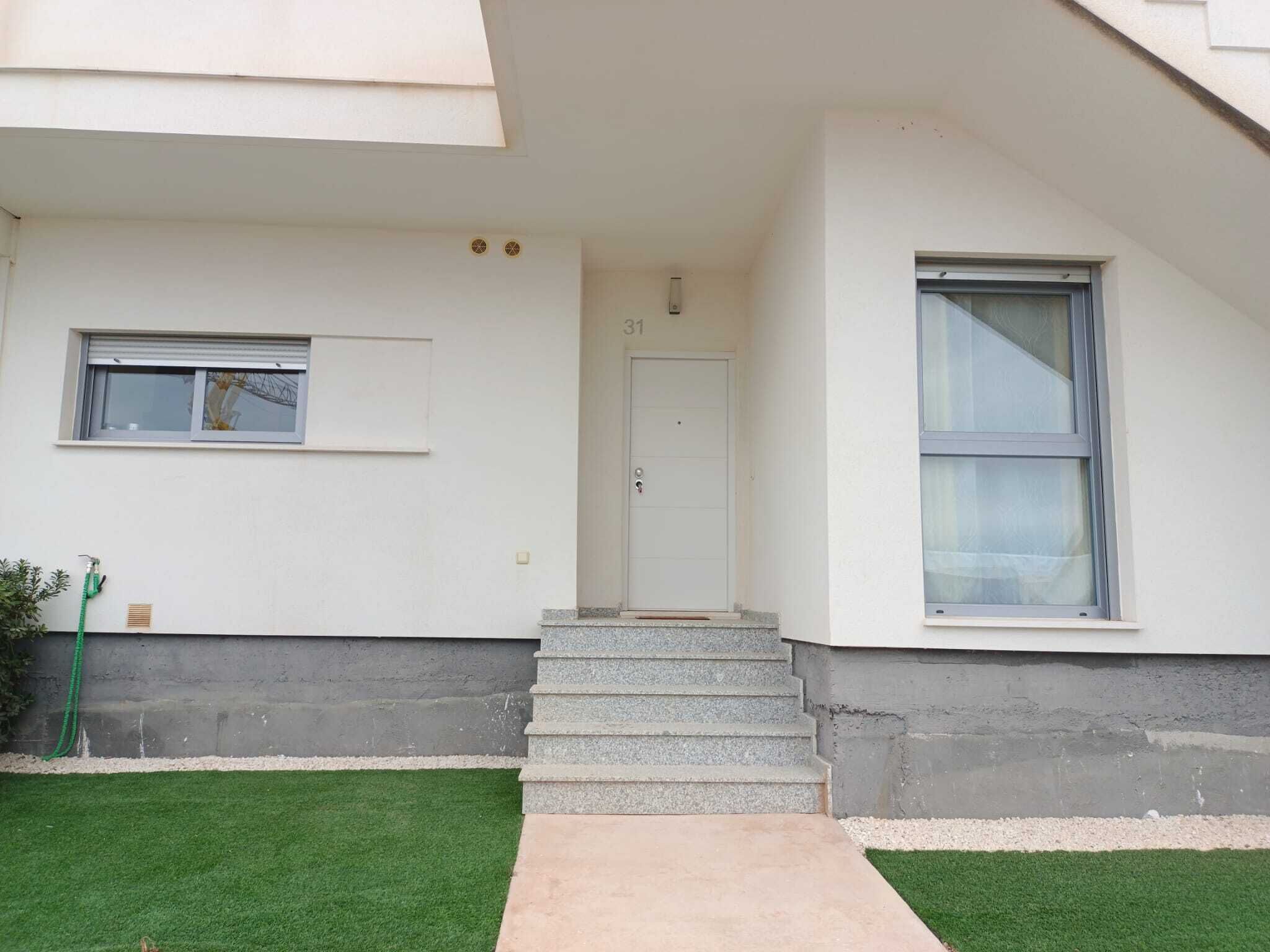 A modern house with a white exterior, a front door, a small window, and a concrete staircase leading to the entrance.