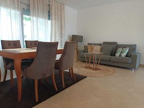 A living room with a dining table, chairs, a sofa, and a coffee table.