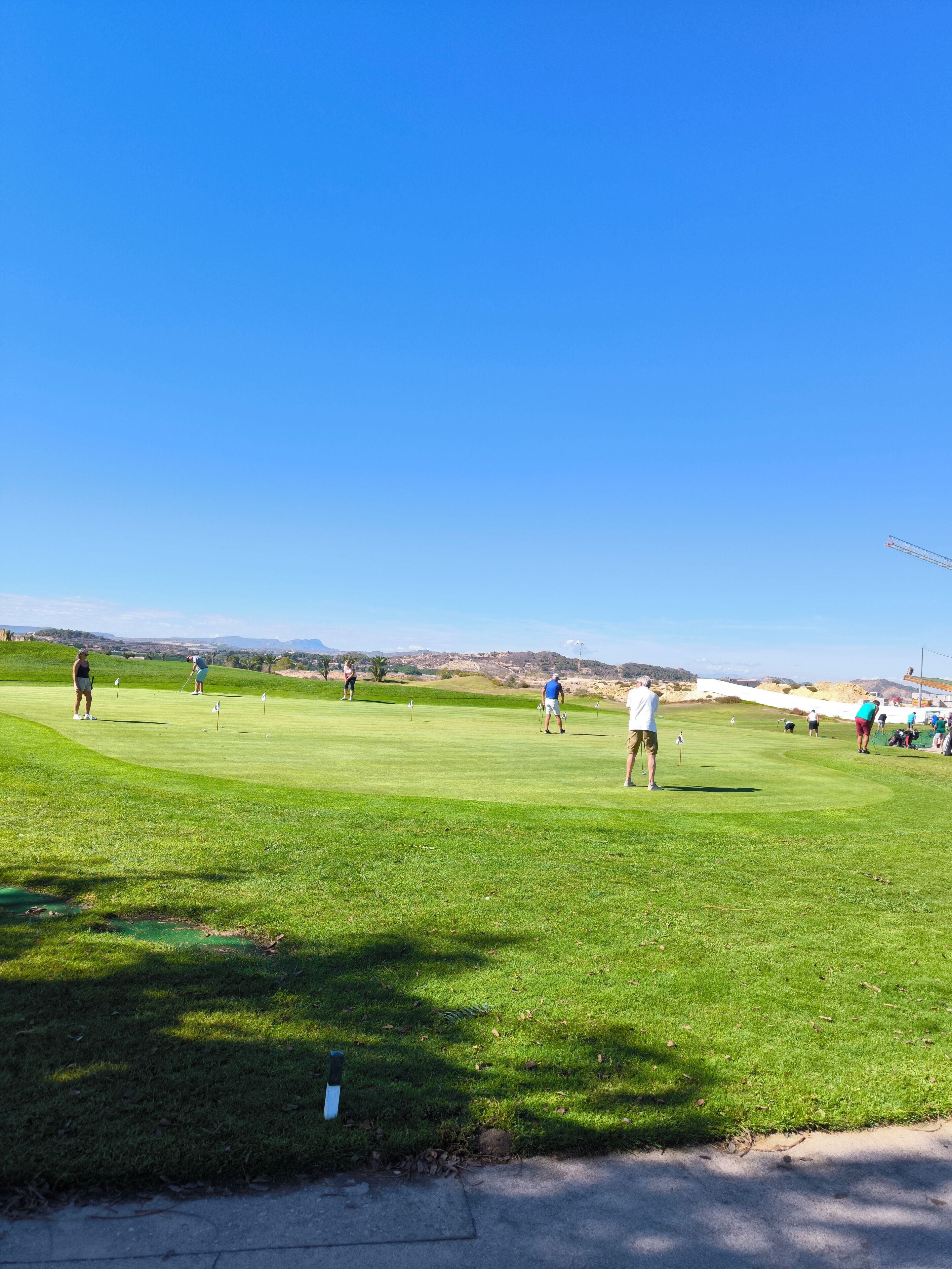 A golf course with players and a clear blue sky.