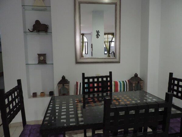 A dining area with a glass-top table, black chairs, and a mirror above. - Stunning Vacation Rental in Cáceres, España (Cáceres)