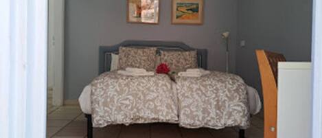 A bedroom with a bed, a nightstand, and two framed pictures on the wall.