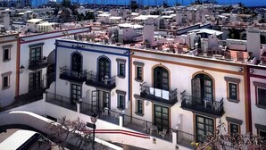 A coastal town with white buildings, balconies, and a clear blue sky.