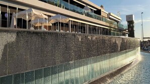 Ein Gebäude am Wasser mit einem Restaurant namens "Gastro Gallery" und einer Terrasse mit Sonnenschirmen.
