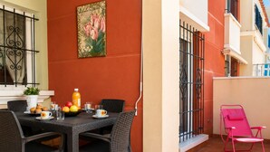 A dining area with a table set for two, a potted plant, and a painting on the wall. - Beach & Pool Av Mancha (Torrevieja)