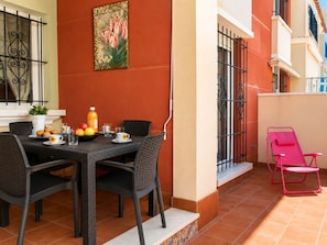 Un coin repas avec une table dressée pour deux personnes, une plante en pot et un tableau accroché au mur.