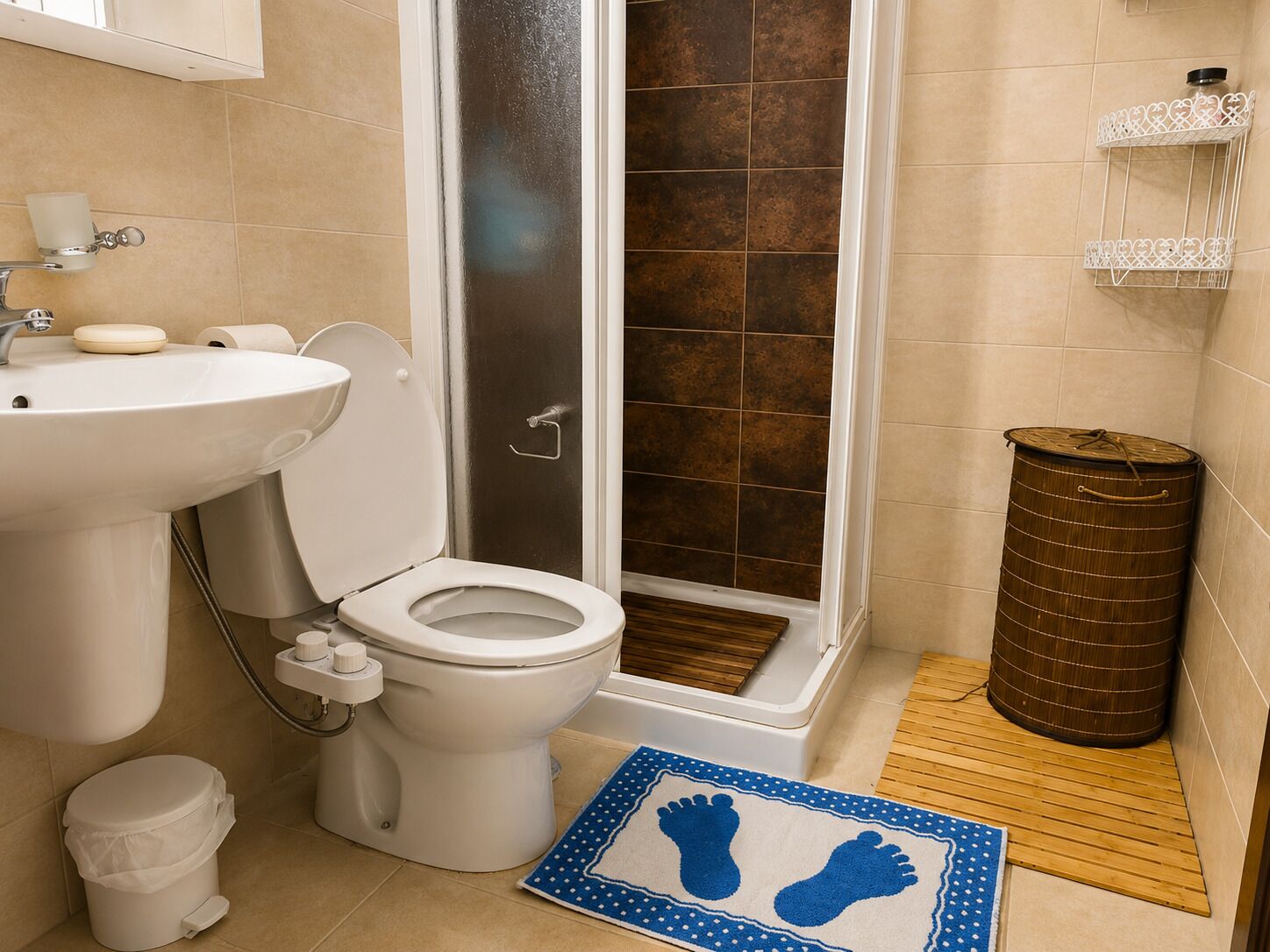 Une salle de bain équipée de toilettes, d’un lavabo, d’une douche et d’une poubelle.