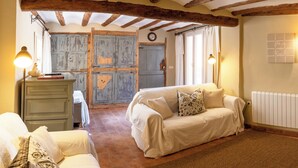 A cozy room with a rustic wooden ceiling, a white sofa with floral cushions, a green dresser, and a large window with curtains. - Experience the Rural Spain With Wine, Activities and More at Sidro & Co (Secastilla)