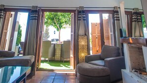 Amplia sala de estar con techo alto, vigas de madera y chimenea. Varios ventanales ofrecen luz natural y vistas al exterior.