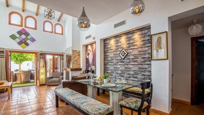 Un salón espacioso con una mesa de comedor preparada para cuatro personas, una banca y un amplio ventanal.