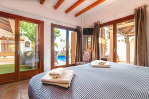 A bedroom with a large bed, a TV, and a view of a pool and outdoor seating area. - Special-offer Luxuriousvilla, Baños y Mendigo, Spain-perfect for Families&groups (Murcia)