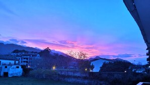 A rural landscape with houses and a mountain range during twilight.