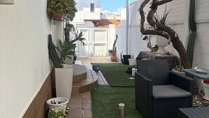 A patio area with a table and chairs, potted plants, and a small garden. - Beach House Apartment (Mairena del Aljarafe)
