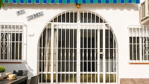 A building with a large arched entrance, a tiled patio, and a table with chairs. - Charming House With Nature (Torrevieja)