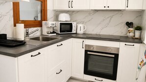 A modern kitchen with white cabinets, a built-in oven, a microwave, and a coffee maker. - Charming House With Nature (Torrevieja)