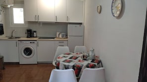 A compact kitchen with a washing machine, a coffee maker, and a refrigerator.