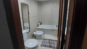 Een moderne badkamer met toilet, hygiëneschuimer en bad.