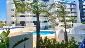 Un hotel moderno con piscina, palme e ringhiera blu.