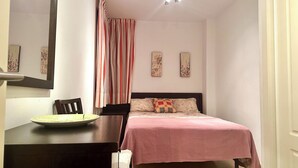 Una camera da letto con un letto, una scrivania con sedia, uno specchio e una doccia.