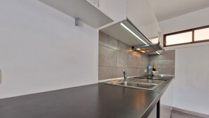A modern kitchen with a stainless steel countertop, a built-in sink, and a range hood. - 413 Cumana2 Puerto Rico By Alquiler de Sùeño (Mogan)