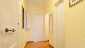 Un pasillo con suelo de baldosas, puertas blancas y un cuadro en la pared.