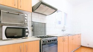 Una cocina con estufa, dos microondas y armarios de madera.