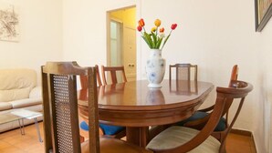 Un comedor con una mesa redonda de madera, seis sillas y un jarrón con flores.