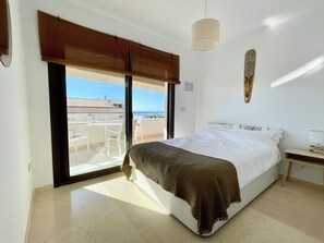 A bedroom with a bed, a nightstand, a lamp, a window with a view of the sea, and a ceiling fan. - Beautiful Flat With a Wonderful View Close to the Beach (Marbella)