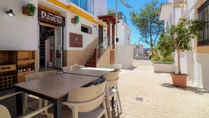 An outdoor seating area with a table and chairs, a staircase, and a building with signs for 'Daver's' and 'PUERTO GIR'. - Room in Guest Room - Private Room in the Fishing Port of Marbella (Marbella)