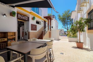 An outdoor seating area with a table and chairs, a staircase, and a building with signs for 'Daver's' and 'PUERTO GIR'. - Room-private Room in the Fishing Port of (Marbella)
