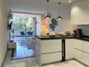 Een moderne keuken met een centraal eiland, hanglampen en uitzicht op de omgeving.