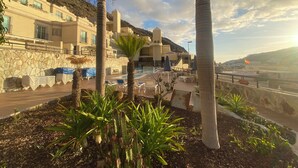 A resort with a pool area, palm trees, and a mountainous backdrop. - Recently Renovated Family Duplex Overlooking the Pool (Mogan)