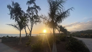 A sunset view with trees and a paved walkway. - Recently Renovated Family Duplex Overlooking the Pool (Mogan)