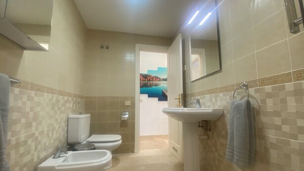 Ein Badezimmer mit zwei Toiletten, einem Waschbecken und einem Spiegel.