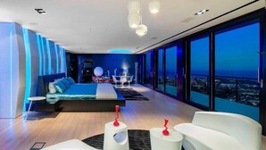 Une chambre moderne dotée d’un grand lit, d’un coin salon et offrant une vue sur la ville la nuit.