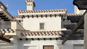 A residential property with a tiled patio, a wooden door, and outdoor seating. - The Fairways - Luxurious Front Line Villa on Mar Menor Golf Resort (Torre-Pacheco)