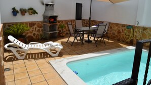 A pool area with a barbecue grill, lounge chairs, and a table with an umbrella. - La Reconquista, Despeñaperros (Santa Elena)