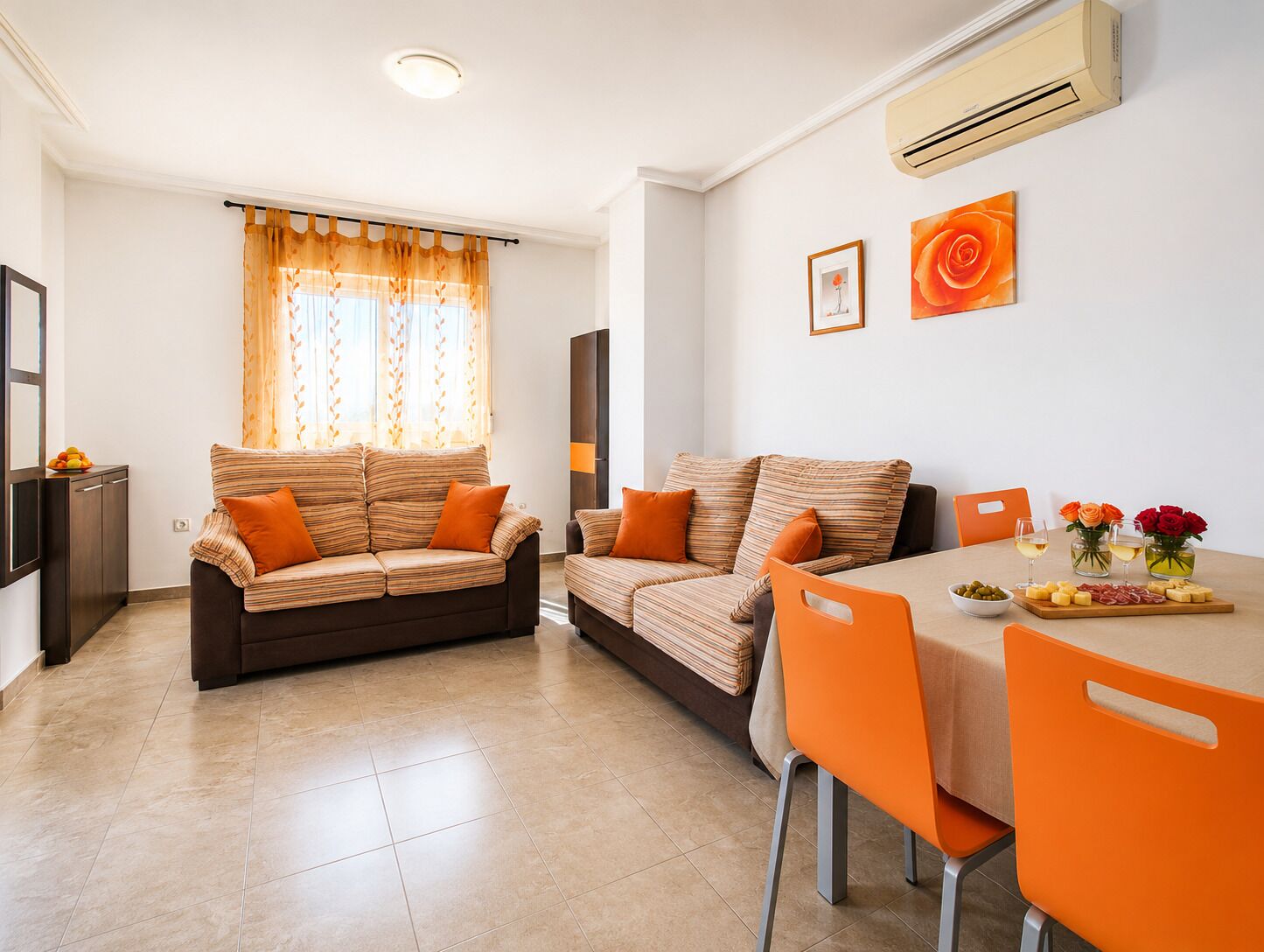 A modern living room with two sofas, a dining table, and a kitchen area.
