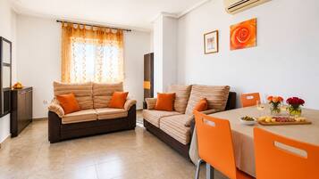 A modern living room with two sofas, a dining table, and a kitchen area.